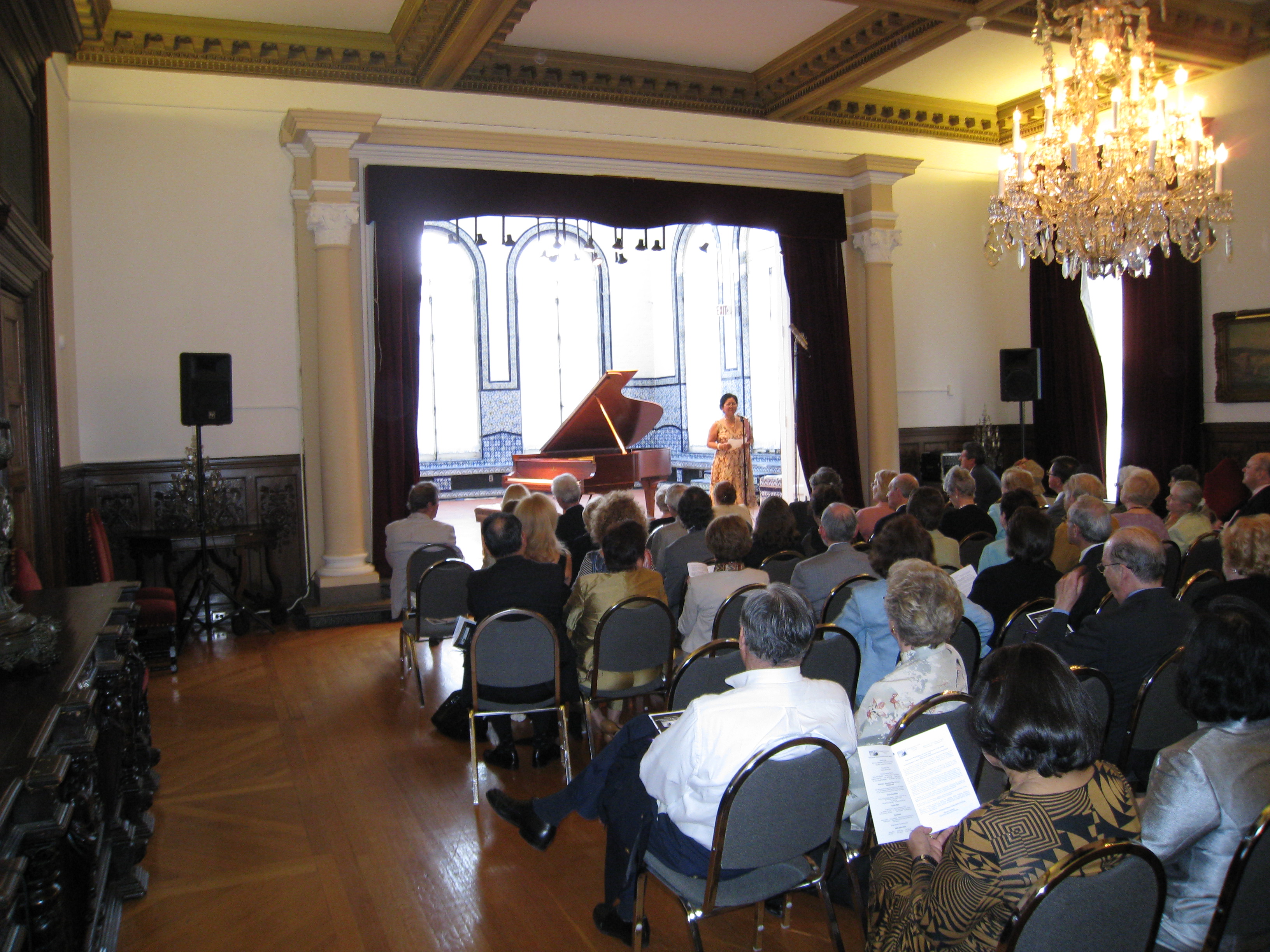 A WIPAC concert in a grand chandeliered hall, the audience seated before the stage and grand piano
